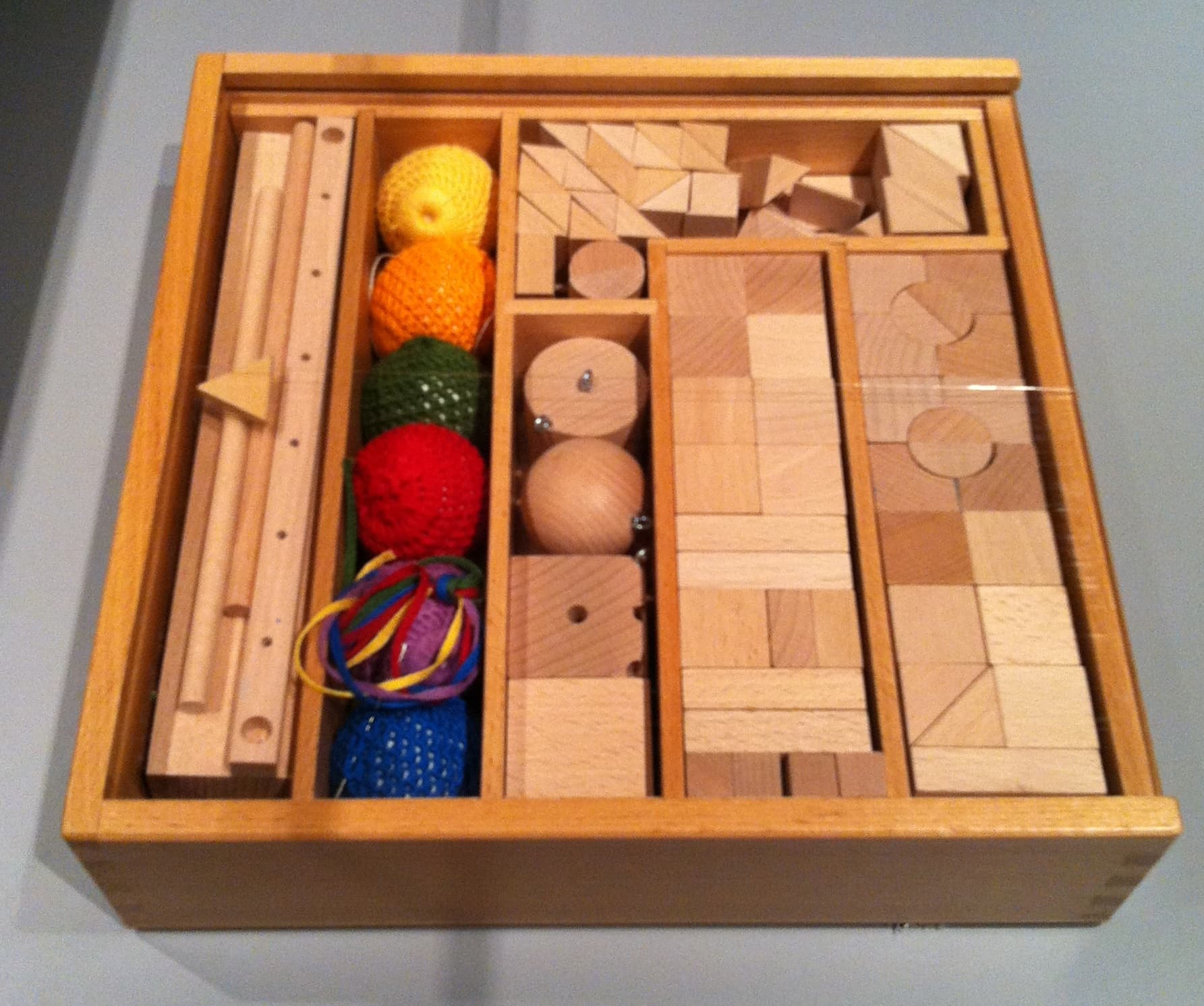 Caja de madera con los bloques y pelotas tejidas del kit de construcción de Friedrich Fröbel